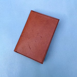 closed tan travel wallet on sky blue background